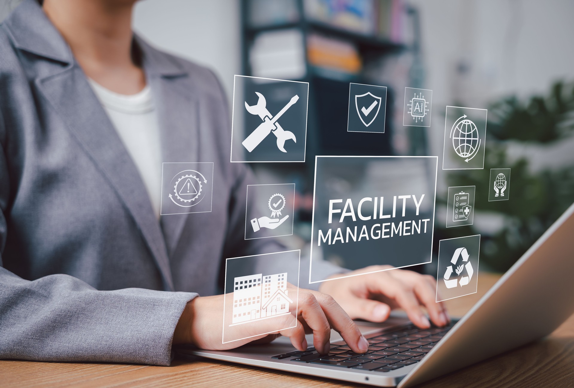 Facility Management Concept. Professional works on laptop with digital icons representing facility management, security, maintenance tools, AI, sustainability, safety, and smart building operations.