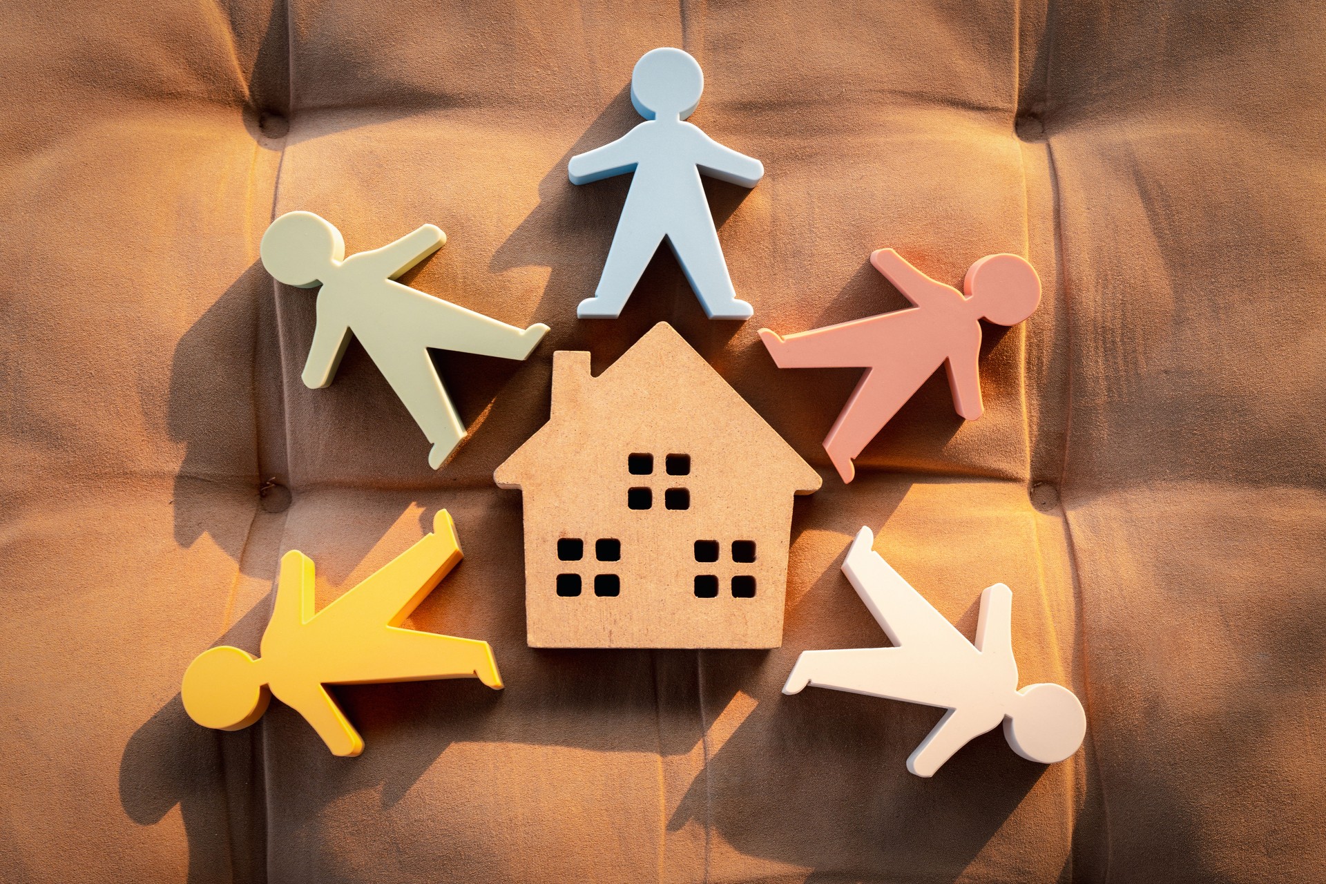 Model of a wooden house and a model of people surround the house.
Concept of happy family, People living and caring for homes, buying, mortgages, and real estate investments.